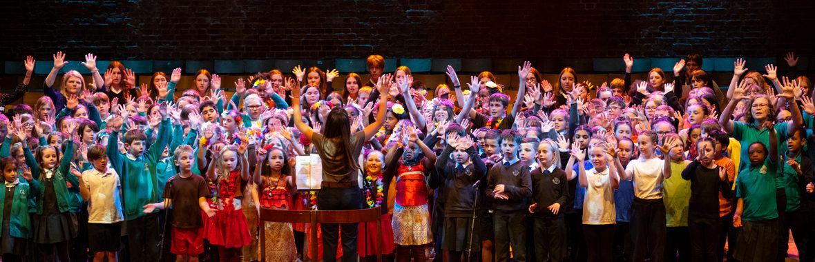 A group of kids singing and raising their hands.