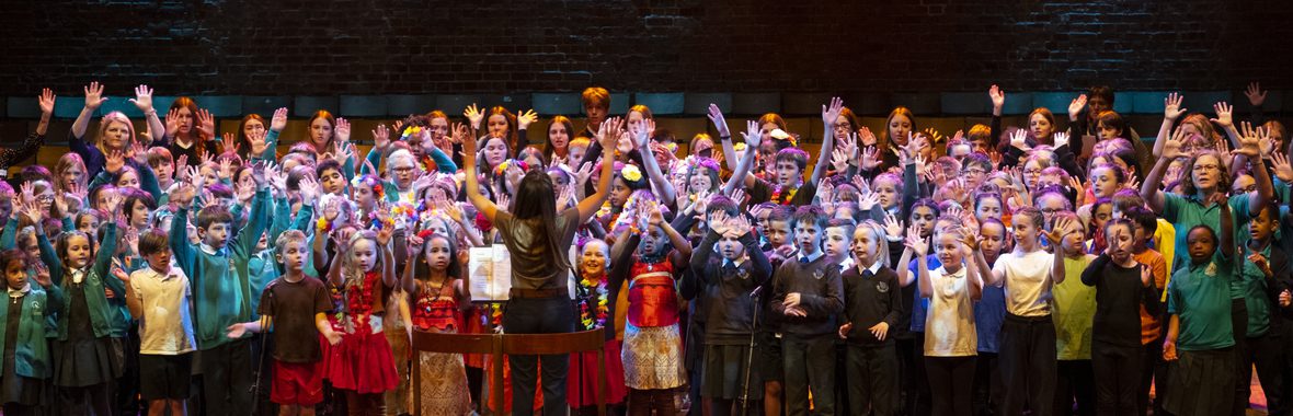 A group of kids singing and raising their hands.