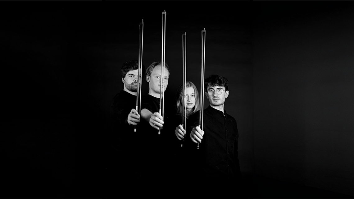 Fibonacci Quartet in black and white, standing side-on and looking at the camera holding up their bows.