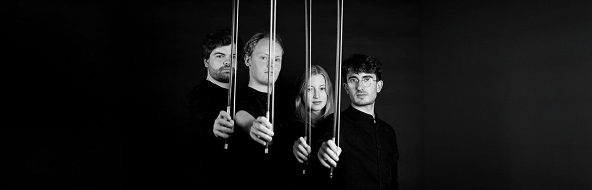 Fibonacci Quartet in black and white, standing side-on and looking at the camera holding up their bows.