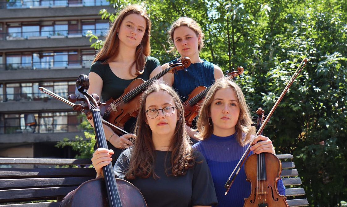 Sonas Quartet sitting and standing in a group holding their string instruments.