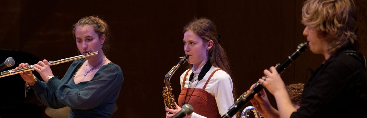 Three young musicians playing instruments against a black background.