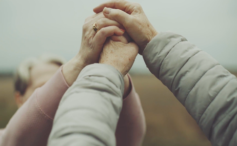 Two people holding both of their hands together.