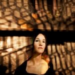 young woman with dark hair bathed in shadows and light