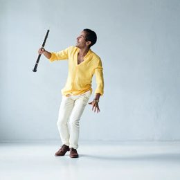 Man wearing white trousers and a yellow shirt holding a