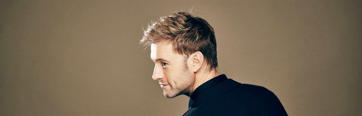 Side view of man with blond hair wearing a dark jacket.