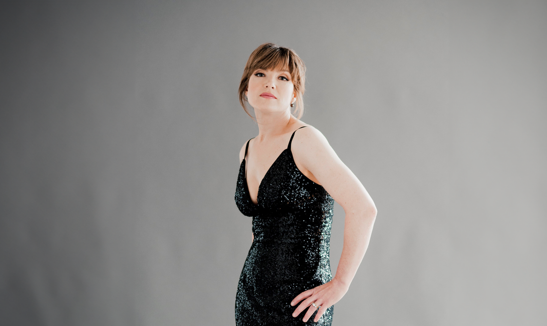 Woman wearing a black, sparkly dress and looking at the camera