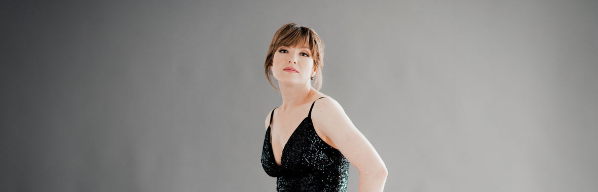 Woman wearing a black, sparkly dress and looking at the camera