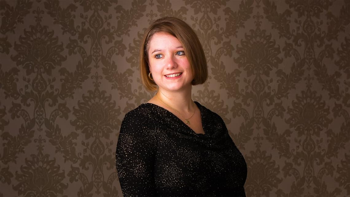 Woman with bobbed brown hair, wearing a sparkly black top, smiling and looking away from the camera.