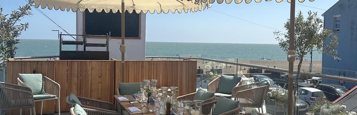 dining table and chairs on terrace with sea view in the background.