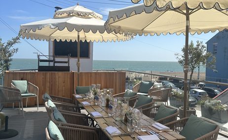 dining table and chairs on terrace with sea view in the background.