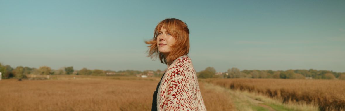 Young woman with red hair standing amidst the reeds.