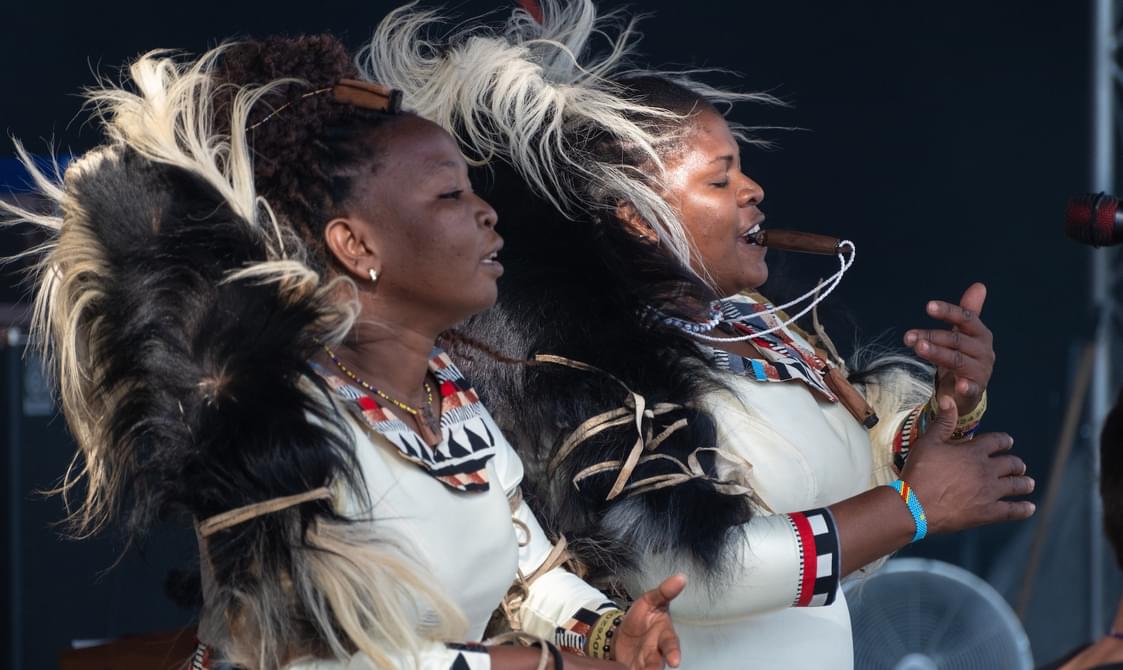 Two women wearing traditional dress and playing instruments.