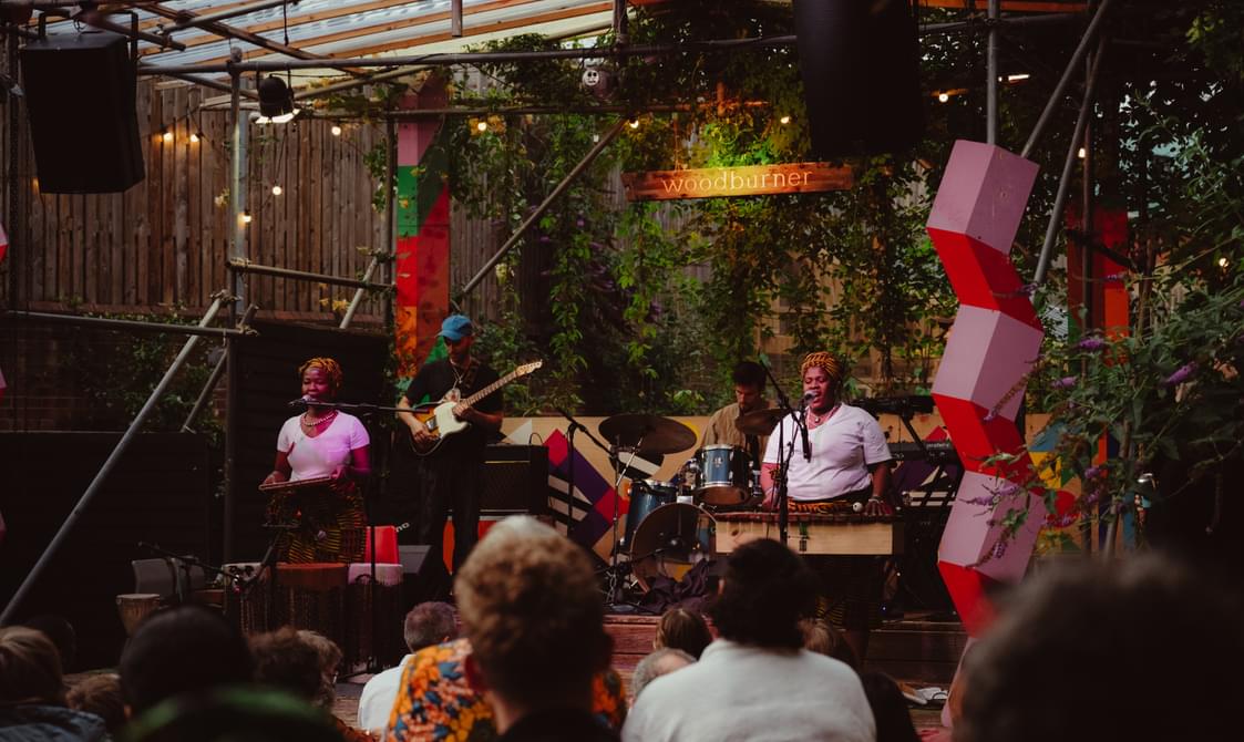 Two women in tshirts performing onstage with their band.