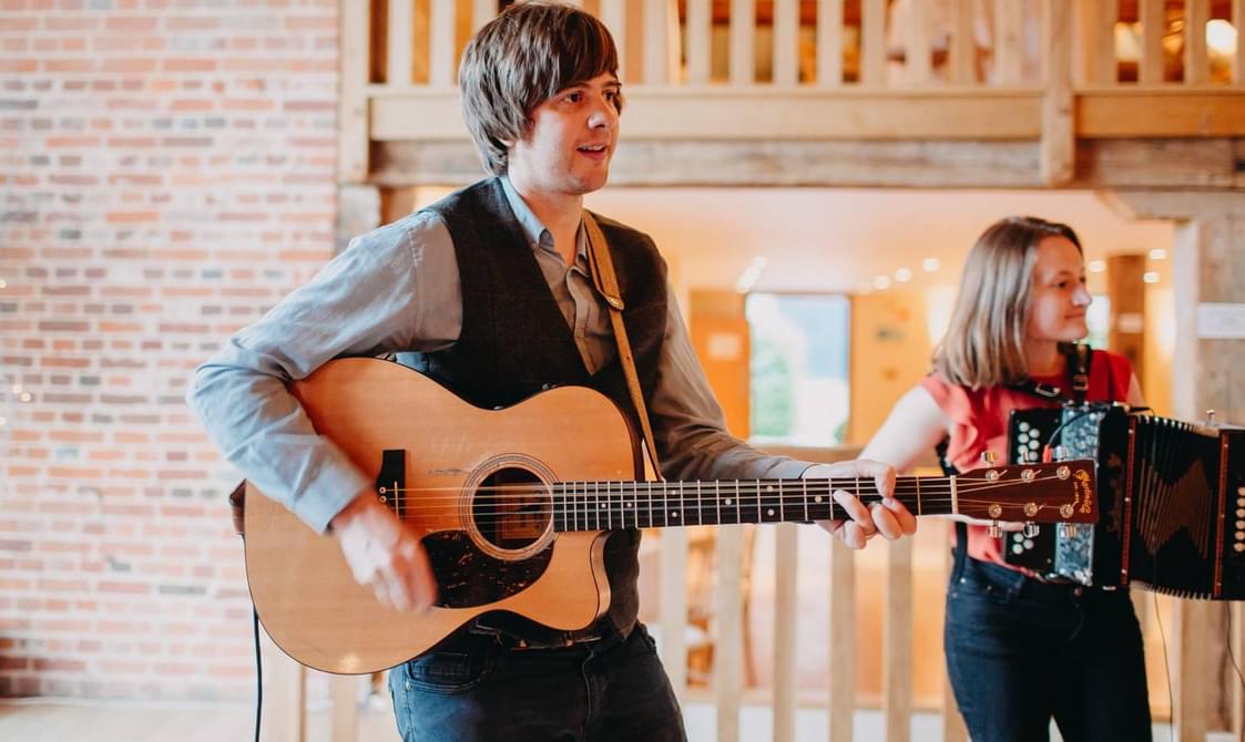 Man with short brown hair playing the guitar.