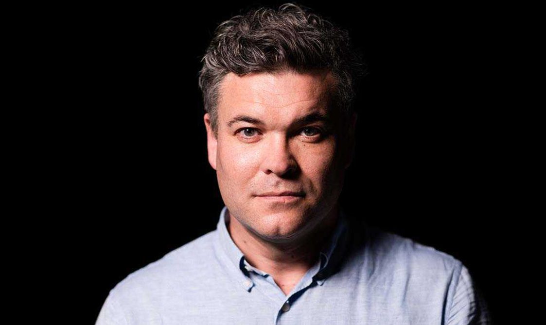 Main with short brown hair wearing a blue shirt.