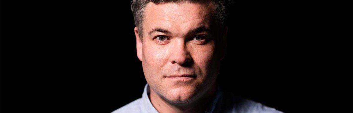 Main with short brown hair wearing a blue shirt.