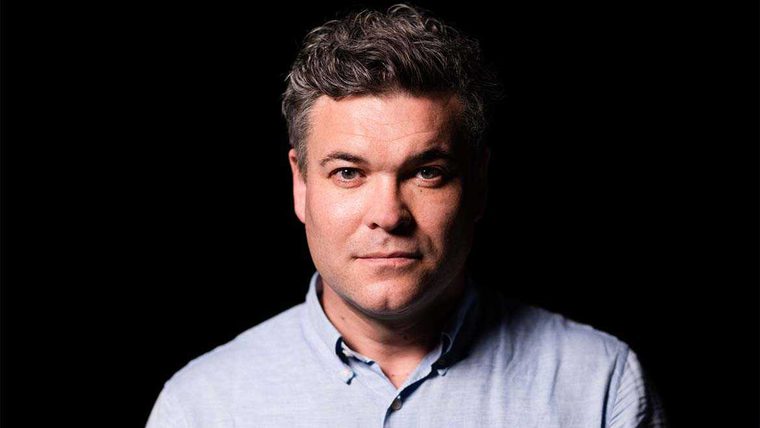 Main with short brown hair wearing a blue shirt.