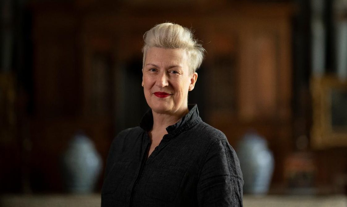 Woman with short blonde hair wearing a black shirt and smiling.