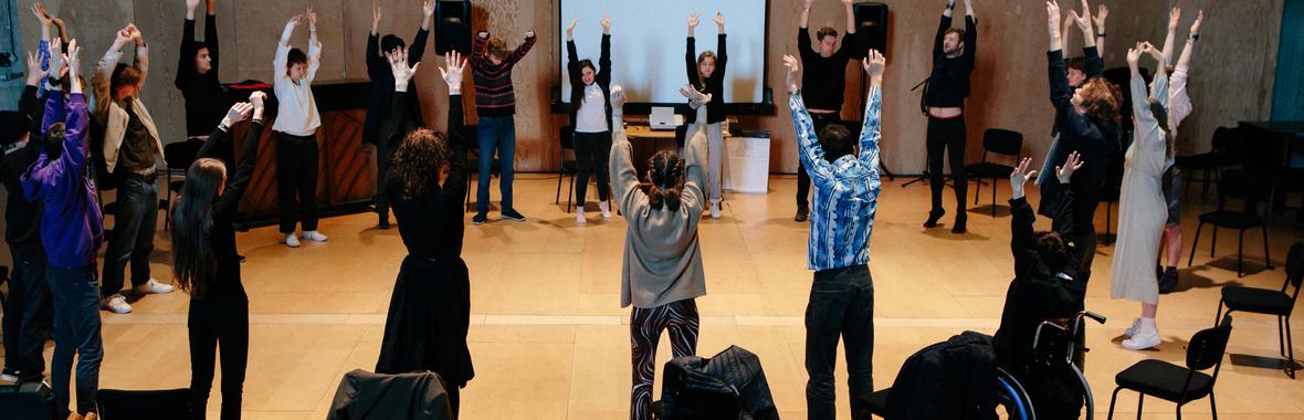 Group of young people standing in a circle with their arms raised