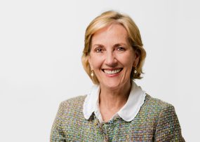 Angela Mallinson, woman with short blonde hair, wearing a suit jacket and smiling.