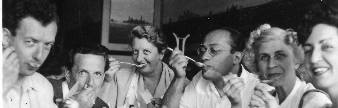 black and white image of a group of performers sitting at a coffee table.