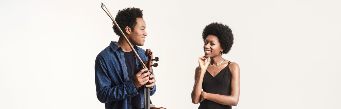 Man holding a cello and smiling at a woman standing beside him