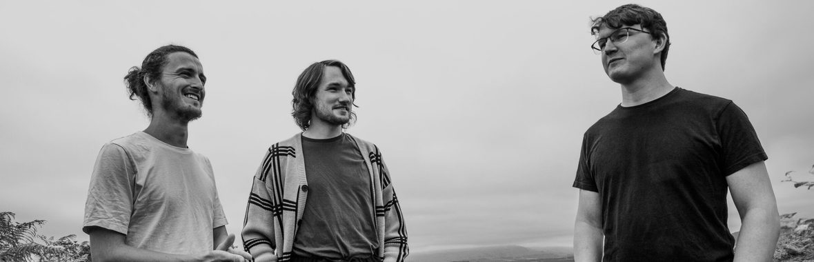 black and white image of three men standing outside together smiling