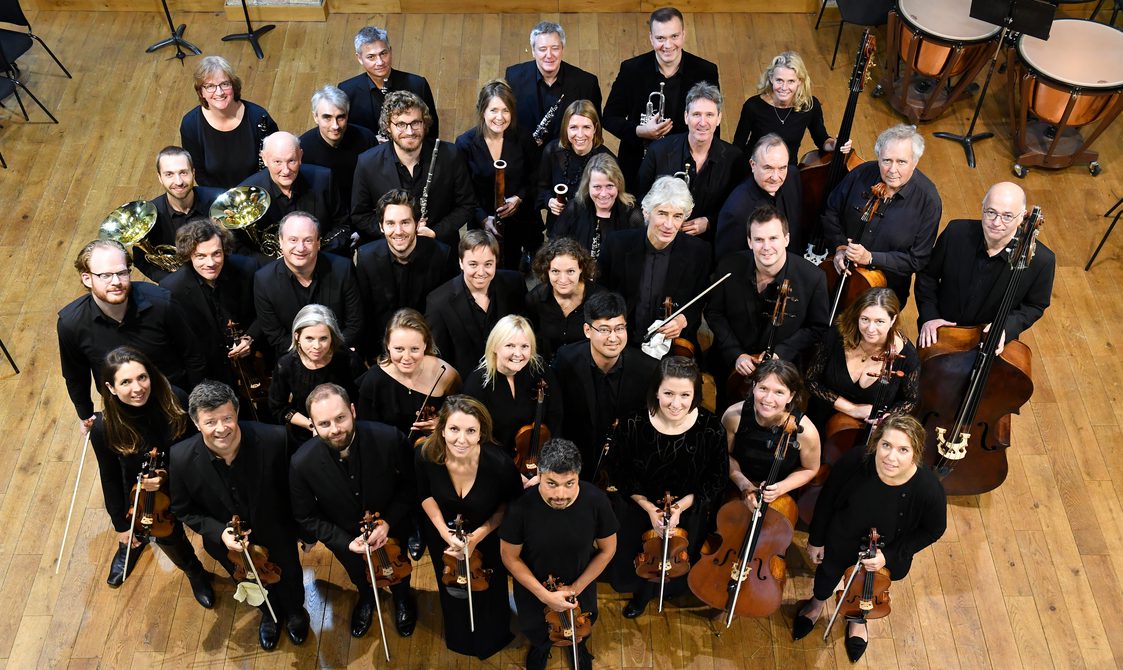 Musicians from English Chamber Orchestra standing in a group, holding their instruments and looking up at the camera.