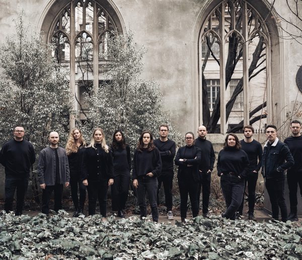 Group of men and women wearing black, standing in front of a church.
