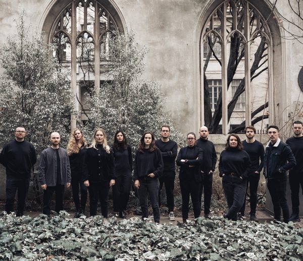 Group of men and women wearing black, standing in front of a church.