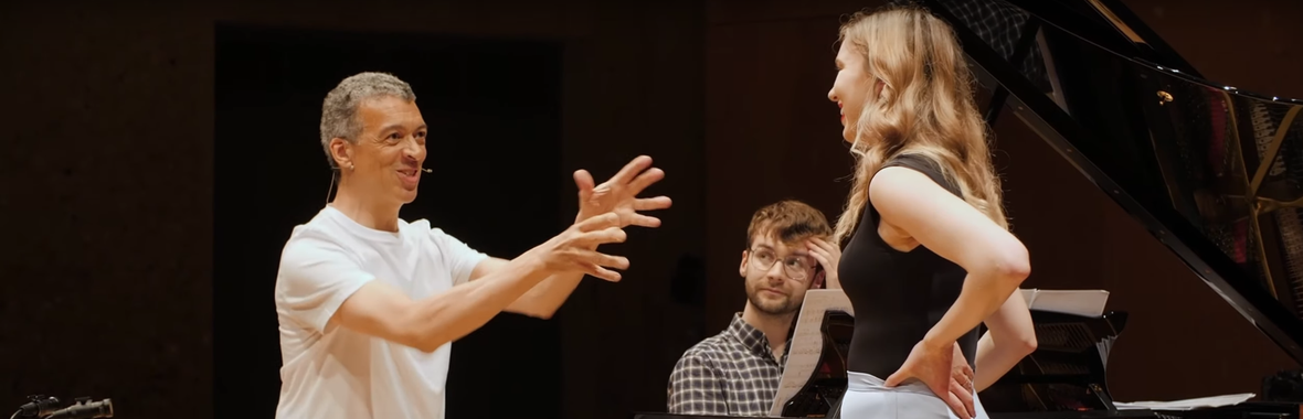 Man in white tshirt interacting with two musicians.