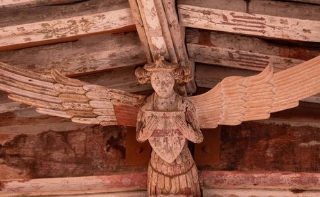 Close-up of a statue of an angel with widespread wings, wearing a crown and holding a shield