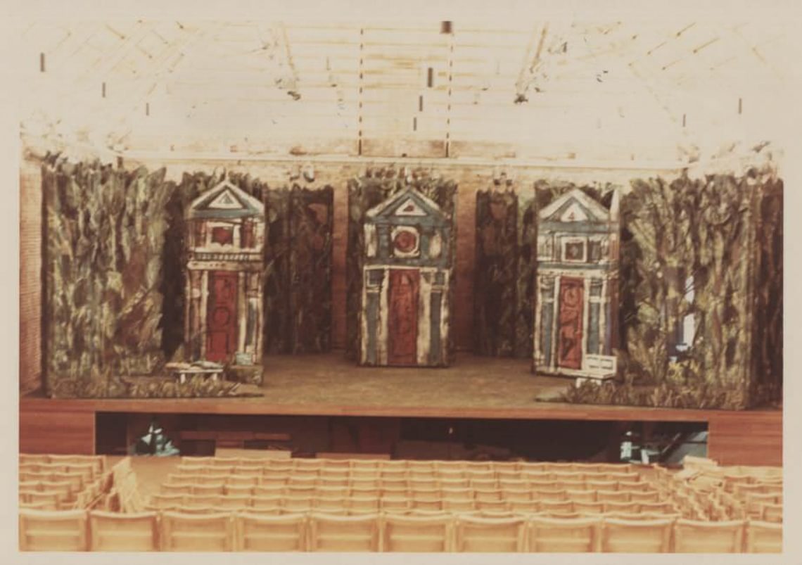 Three buildings on a stage with empty seats in the foreground