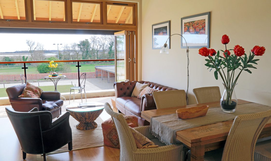 Interior view of lounge, leather chairs and cream fabric sofa, dining chairs and table with red tulips