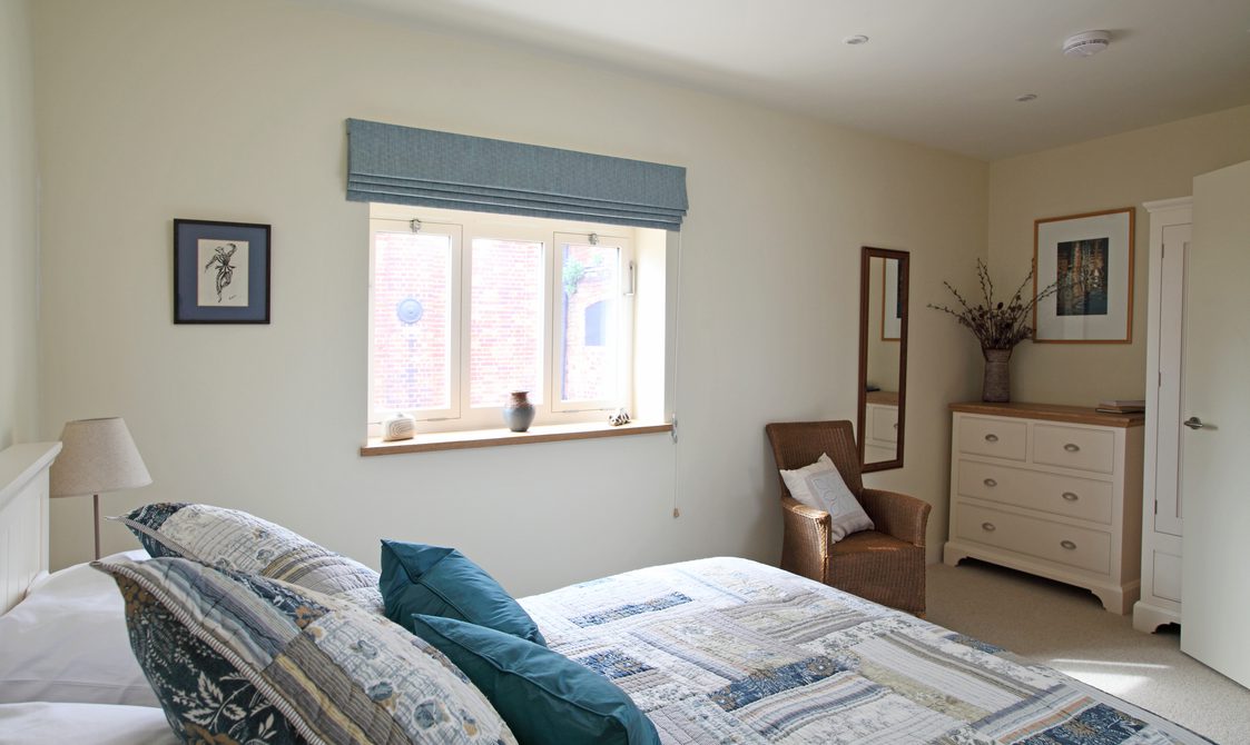 Interior view of bedroom with window, cupboards and double bed