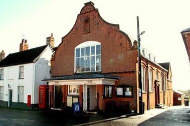 A red brick building with an interesting shaped roof. Beach in the background.
