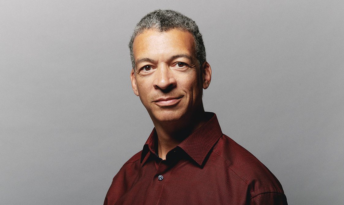 Main with short hair wearing a red shirt looking into the camera.