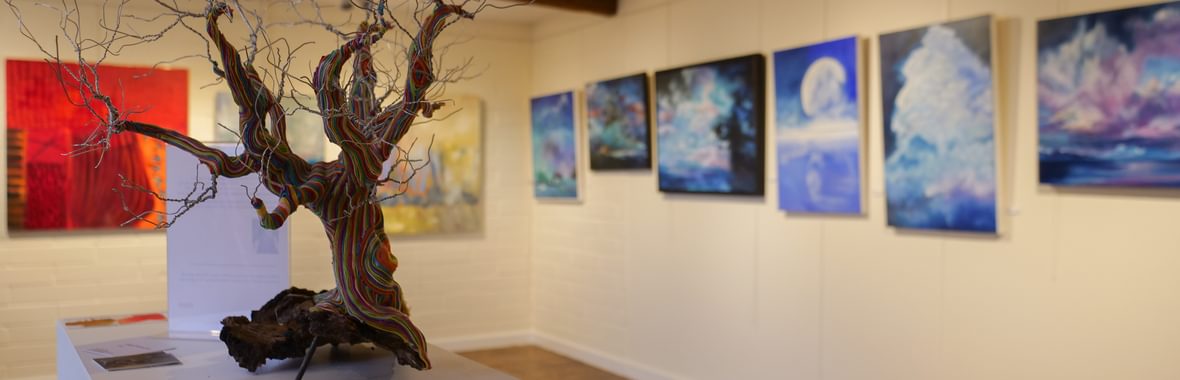 A picture of the gallery, with a small tree piece in the foreground.