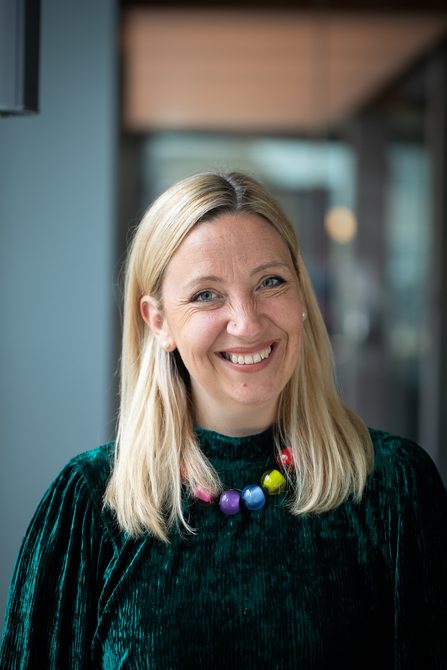 Woman with long blonde hair smiling.