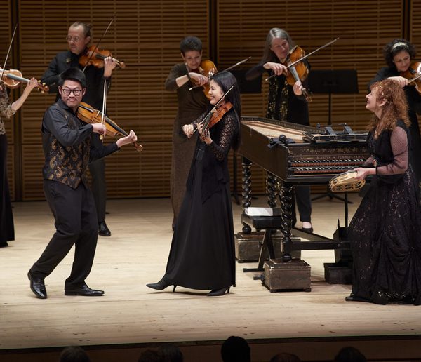 Group of musicians onstage, playing instruments and smiling.