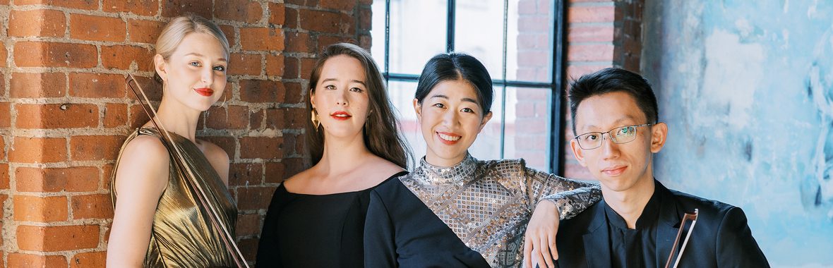 Terra Quartet, three women and one man standing close together against a brick wall and window.