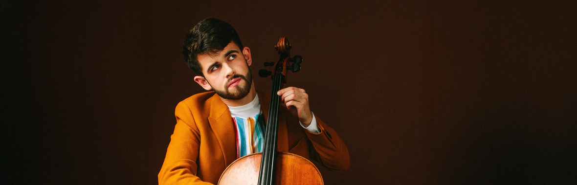 Hugh Mackay, man with short dark hair and beard wearing a brown jacket and holding a cello.