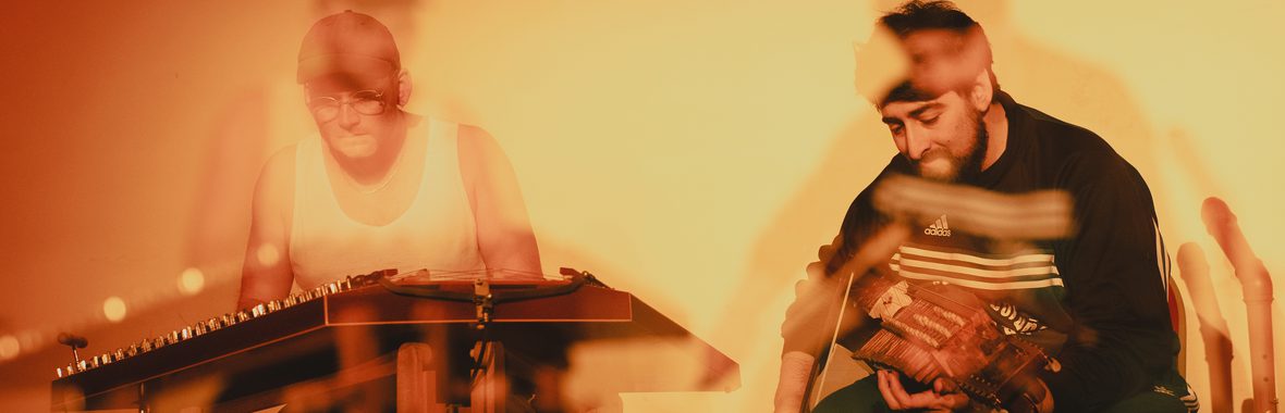 Blurry image of two men playing musical instruments.