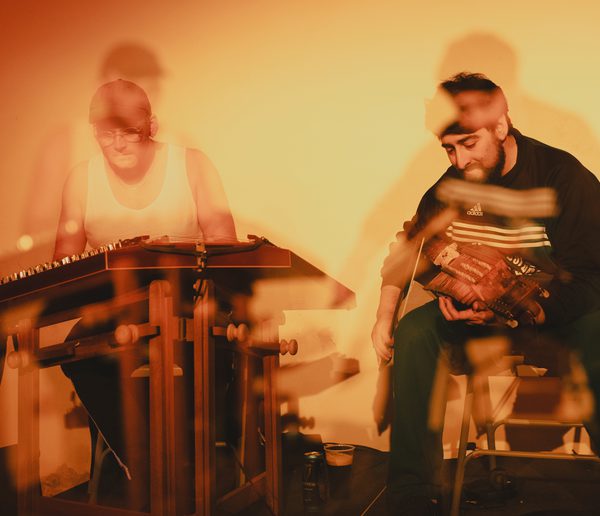 Blurry image of two men playing musical instruments.