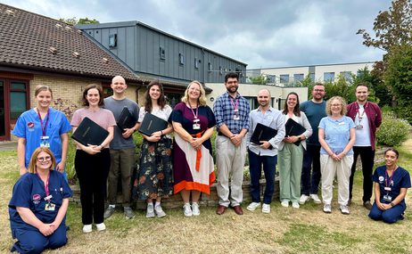 Sansara Choir group of men and women standing together in a row outside and smiling at the camera