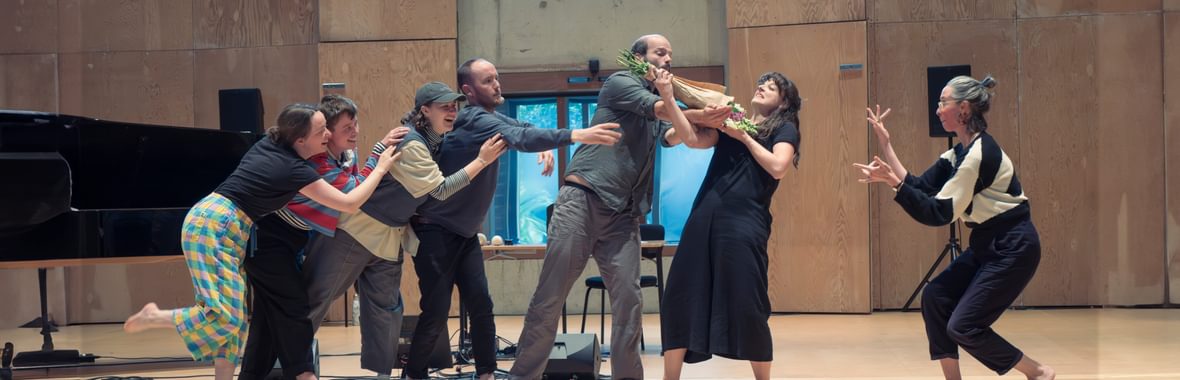 Seven Voicebox performers posing in a group inside a hall