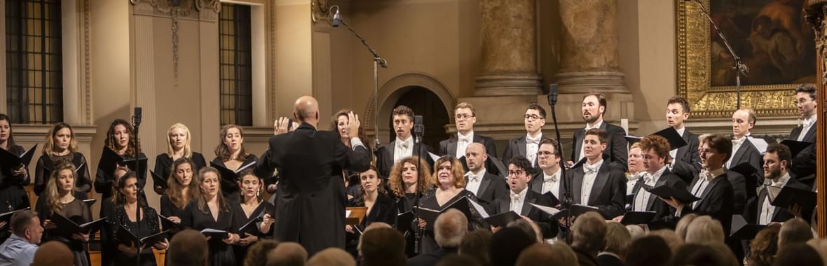 Choir of men and women singing in an ornate church.