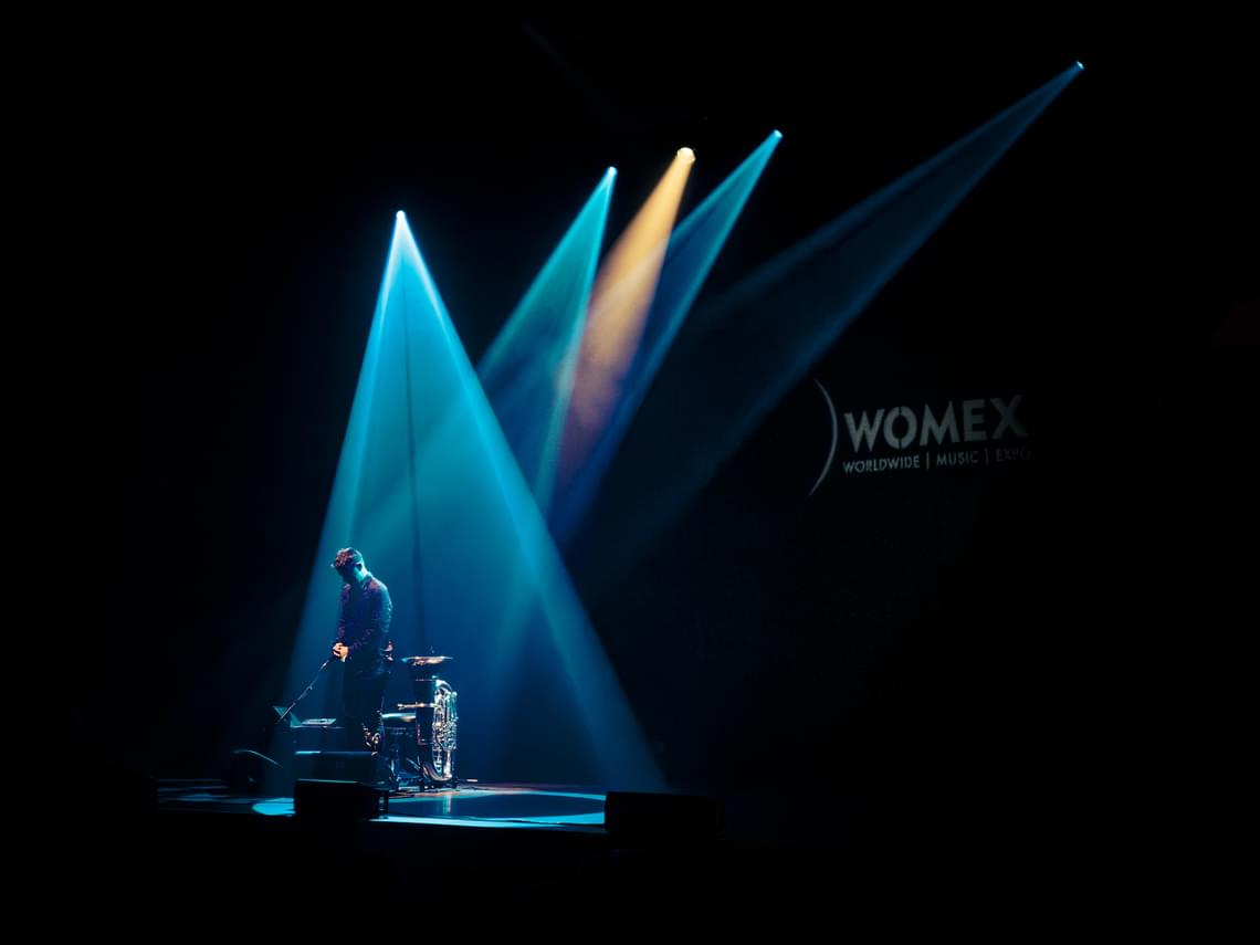 Man onstage with a tuba, silhouetted by blue spotlights.
