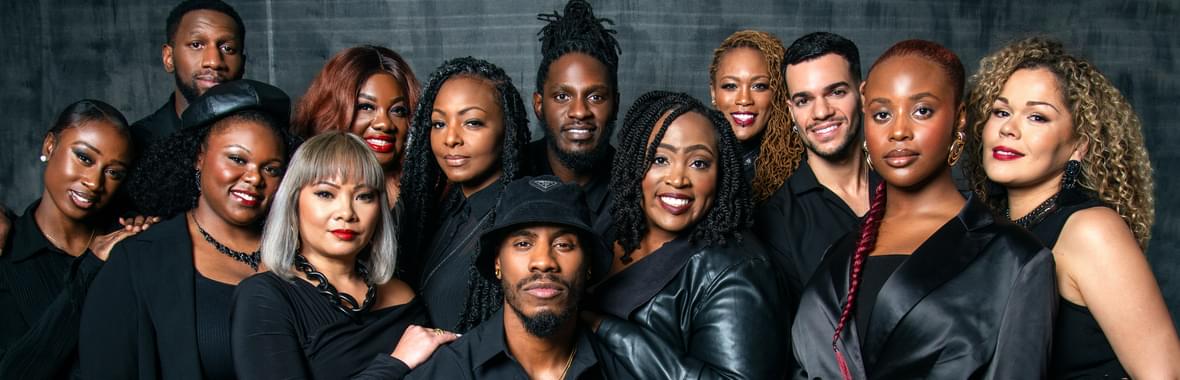 Group of men and women wearing black, standing close together and smiling.